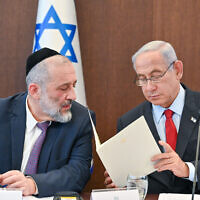 Prime Minister Benjamin Netanyahu (right) reads a letter to Shas chair Aryeh Deri, informing Deri that he must remove him from ministerial office, at the weekly cabinet meeting in Jerusalem, January 22, 2023. (Kobi Gideon/GPO)