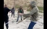 A screenshot from a video shared on social media shows an Israeli settler using a club to attack Palestinians and foreign hikers, near the West Bank city of Jericho on January 13, 2022. (Screen capture: Twitter; used in accordance with Clause 27a of the Copyright Law)