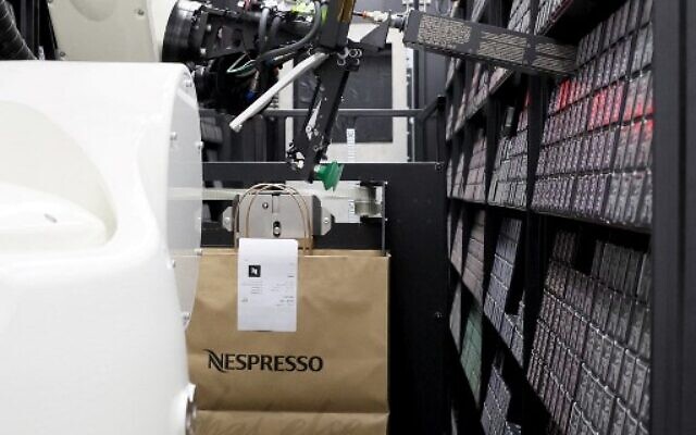 A robot prepares a bag of Nespresso coffee capsules ahead of its distribution to a customer, at the automated storeroom designed by the Israeli company 1MRobotics, in Tel Aviv, January 11, 2023. (JACK GUEZ/AFP)