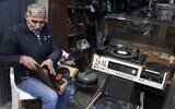 Jamal Hemmou checks a collection of vinyl records in front of his shop in the West Bank city of Nablus, January 17, 2023. (JAAFAR ASHTIYEH / AFP)