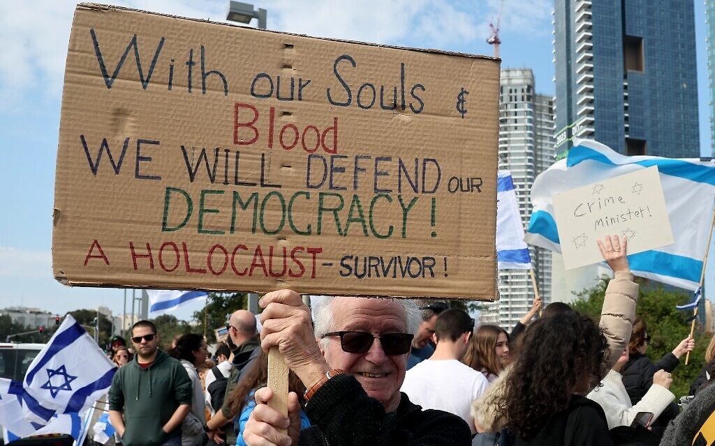 Israeli protesters lift national flags and placards as they rally in Tel Aviv on February 13, 2023, against controversial legal reforms being advanced by the government. (Photo by JACK GUEZ / AFP)