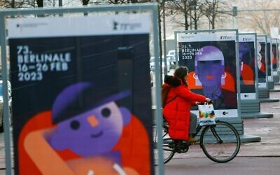 A woman cycles past a row of posters of the upcoming Berlinale 73rd International Film Festival in Berlin on February 15, 2023. (David GANNON / AFP)