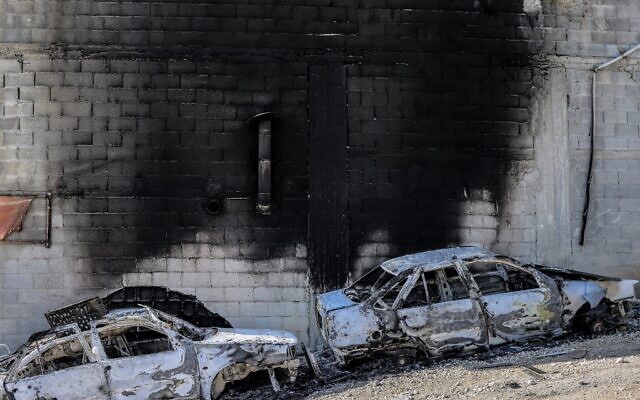 This picture taken on February 27, 2023, shows a view of torched cars and a building in the town of Huwara near Nablus in the West Bank. (Photo by RONALDO SCHEMIDT / AFP)