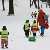 Young children pull a sledge as they walk up a slope through snow in the western Ukrainian city of Lviv on February 7, 2023, amid the Russian invasion of Ukraine. (Yuriy Dyachyshyn/AFP)