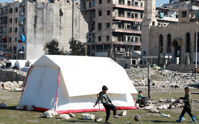 Children, displaced as a result of the earthquake that hit Turkey and Syria earlier this month, play football outside a tent at a make shift camp in Bustan al-Basha neighborhood in the government-held northern city of Aleppo, Syria, on February 20, 2023. (LOUAI BESHARA/AFP)