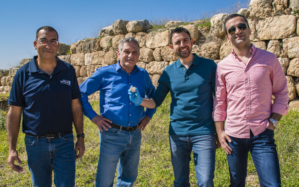 From right to left, Yakov Ashkenazi, Eylon Levy, Dr. Haggai Misgav, and Saar Ganor with the potsherd at Tel Lachish, revealed by the Israel Antiquities Authority on March 1, 2023. (Yoli Schwartz/IAA)