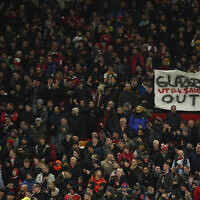 An anti-Glazer family banner is held up by members of the crowd before the English League Cup semifinal second leg soccer match between Manchester United and Nottingham Forest at Old Trafford in Manchester, England, Wednesday, Feb. 1, 2023 (AP Photo/Dave Thompson)