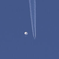 A large balloon drifts above the Kingstown, North Carolina area, with an airplane and its contrail seen below it. (Brian Branch via AP)