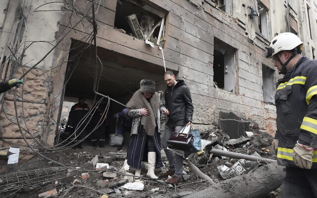 Illustrative: A man helps a woman to walk out from a residential building which was hit by a Russian rocket, in the city center of Kharkiv, Ukraine, February 5, 2023. (AP Photo/Andrii Marienko)