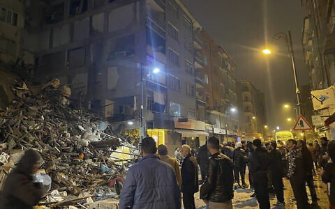 People gather around a collapsed building in Pazarcik, in Kahramanmaras province, southern Turkey, early Monday, Feb. 6, 2023. (Depo Photos via AP)
