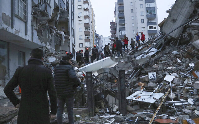 People and rescue teams try to reach trapped residents inside collapsed buildings in Adana, Turkey, Feb. 6, 2023. (IHA agency via AP)
