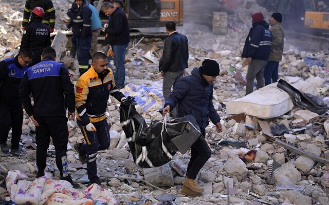 Two men carry a body from a destroyed building in Adana, southern Turkey, February 7, 2023 (AP Photo/Hussein Malla)
