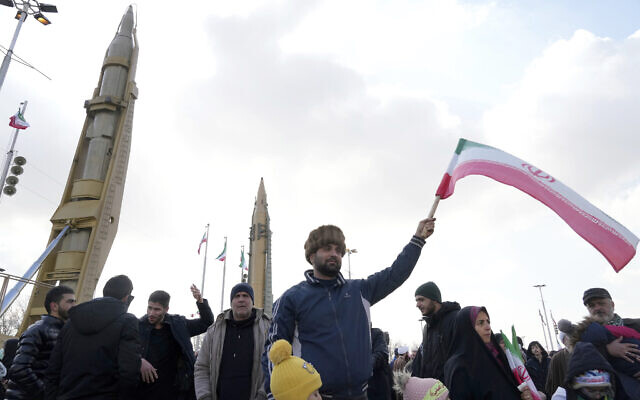 A man waves an Iranian flag as domestically built missiles are displayed in the background during the annual rally commemorating Iran's 1979 Islamic Revolution, in Tehran, Iran, February 11, 2023. (AP Photo/Vahid Salemi)