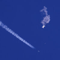 In this file photo provided by Chad Fish, the remnants of a large balloon drift above the Atlantic Ocean, just off the coast of South Carolina, with a fighter jet and its contrail seen below it, Feb. 4, 2023. A missile fired on Feb. 5 by a US F-22 off the Carolina coast ended the days-long flight of what the Biden administration says was a surveillance operation that took the Chinese balloon near US military sites. (Chad Fish via AP, File)