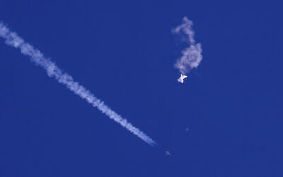 The remnants of a large balloon drift above the Atlantic Ocean, just off the coast of South Carolina, with a fighter jet and its contrail seen below it, February 4, 2023. A missile fired on February 5 by a US F-22 off the Carolina coast ended the days-long flight of what the Biden administration says was a surveillance operation that took the Chinese balloon near US military sites. (Chad Fish via AP, File)