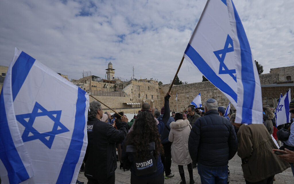 Protesters wave Israeli flags during a demonstration against Prime Minister Benjamin Netanyahu's new government's plans to overhaul the judicial system, at the Western Wall plaza in the Old City of Jerusalem, February 13, 2023. (AP/Ohad Zwigenberg)