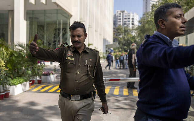 A police officer and a private security guard ask journalists to leave from the gate of a building housing BBC office in New Delhi, India, Tuesday, Feb. 14, 2023 (AP Photo/Altaf Qadri)