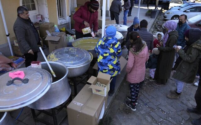 People wait to receive a hot meal, in Iskenderun city, southern Turkey, Tuesday, Feb. 14, 2023 (AP Photo/Hussein Malla)