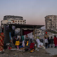 A family stays in a makeshift tent surrounded of buildings that were heavily affected during the earthquake in Antakya, southeastern Turkey, February 14, 2023. (Bernat Armangue/AP)