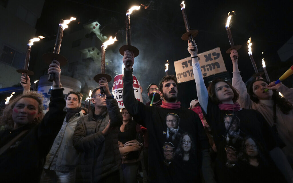 Israelis carry torches during a protest against plans by Prime Minister Benjamin Netanyahu's government to overhaul the judicial system, in Tel Aviv, Israel, February 18, 2023. (AP Photo/Tsafrir Abayov)