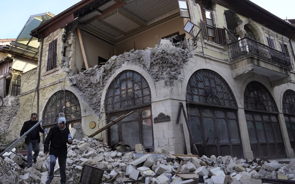 Turkish citizens pass in front of a heritage hotel that destroyed during the devastated earthquake, in the old city of Antakya, southern Turkey, Monday, February 13, 2023. (AP Photo/Hussein Malla)
