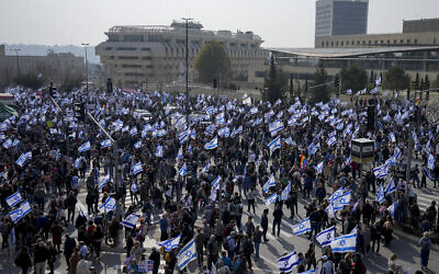 Israelis protest against government plans to overhaul the judicial system outside the Knesset, with the Bank of Israel headquarters seen in the background, February 20, 2023. (AP/Ohad Zwigenberg)