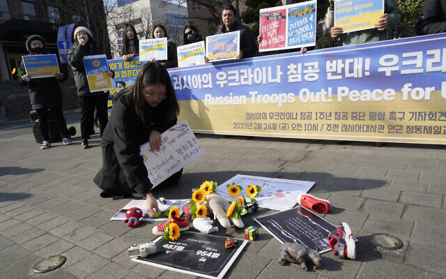 A protester places a flower to pay tribute to children killed in Russia's war against Ukraine during a rally to mark the one-year anniversary of Russia's invasion of Ukraine, near the Russian Embassy in Seoul, South Korea, February 24, 2023. (AP Photo/Ahn Young-joon)