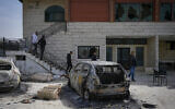 Palestinians inspect a damaged house and scorched cars in the town of Huwara, near the West Bank city of Nablus, February 27, 2023. (AP Photo/Ohad Zwigenberg)