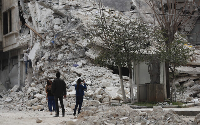 People stand by a building destroyed in recent earthquake in Aleppo, Syria,  February 27, 2023. (Omar Sanadiki/AP)