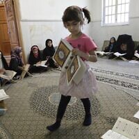 Illustrative: An Iranian girl carries the Quran, Islam's holy book, in a classroom during the Muslim holy fasting month of Ramadan in Tehran, Iran, July 26, 2012. (AP/Vahid Salemi)