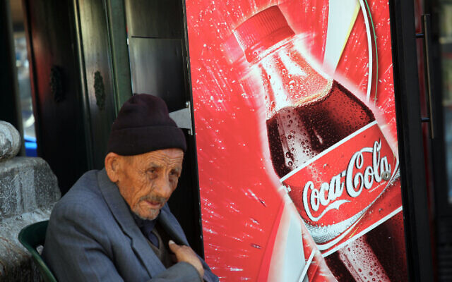 Illustrative: An elderly man sits next to a soda-vending machine selling Coca-Cola in the Old City of Jerusalem. (Yossi Zamir/Flash 90)