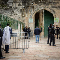 Illustrative: Ultra-Orthodox Jewish men, left, pray as as Israeli police officers guard the entrance to the Al Aqsa Mosque, in Jerusalem's Old City on April 19, 2022. (Yonatan Sindel/Flash90)