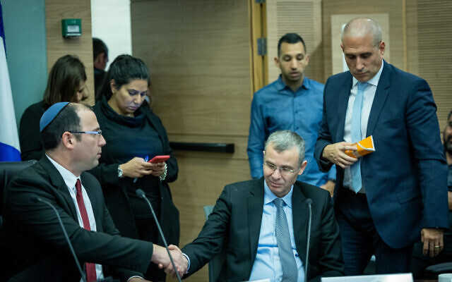 Chairman of the Knesset Constitution, Law and Justice Committee MK Simcha Rothman and Justice Minister Yariv Levin shake hands at a committee hearing, January 11, 2023. (Yonatan Sindel/Flash90)