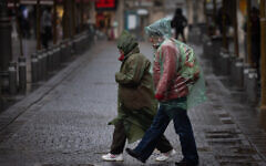 People walk in the rain in downtown Jerusalem, February 1, 2023. (Yonatan Sindel/Flash90)