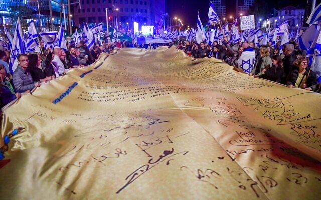 Israelis unfurl a massive copy of the Declaration of Independence at a protest against the Netanyahu government and its planned judicial overhaul in Tel Aviv, February 18, 2023. (Avshalom Sassoni/Flash90)
