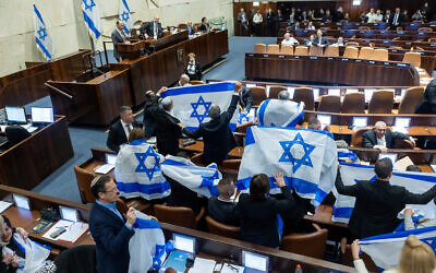 Opposition MKs holding Israeli flags during the discussion and vote on the government's judicial overhaul plans in the Knesset, February 20, 2023 (Photo by Yonatan Sindel/Flash90)