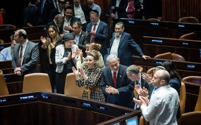 Prime Minister Benjamin Netanyahu (center)  and Justice Minister Yariv Levin celebrate in the Knesset plenum on February 21, 2023. (Yonatan Sindel/Flash90)
