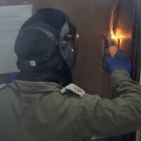 An IDF soldier welds a door shut, in the East Jerusalem neighborhood of A-Tur, February 12, 2023. (Israel Defense Forces)