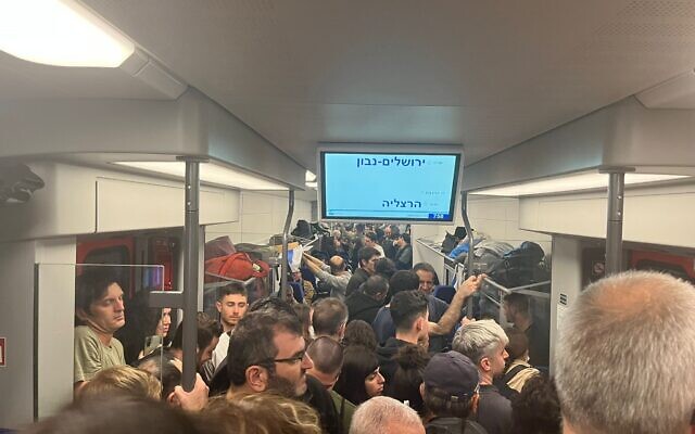 Demonstrators cram onto a train on their way back home from a mass protest in Jerusalem against the government's judicial overhaul plans, February 13, 2023. (Naomi Lanzkron/Times of Israel)