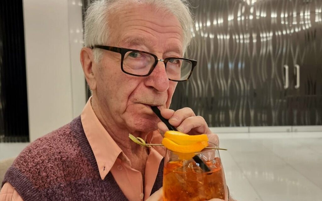 Gidon Lev drinks an Aperol spritz in the hotel lobby during an interview with The Times of Israel, January 24, 2023. (Courtesy of Julie Gray)