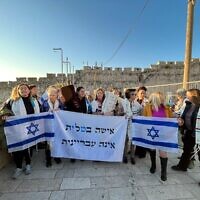 Reform rabbis and supporters of Women of the Wall march to the Western Wall with a sign protesting a bill that would criminalize women wearing prayer shawls at the holy site, on February 22, 2023. (Central Conference of American Rabbis)