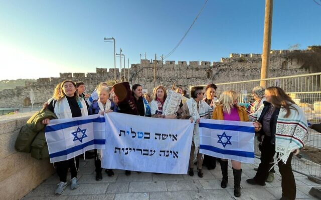 Reform rabbis and supporters of Women of the Wall march to the Western Wall with a sign protesting a bill that would criminalize women wearing prayer shawls at the holy site, on February 22, 2023. (Central Conference of American Rabbis)