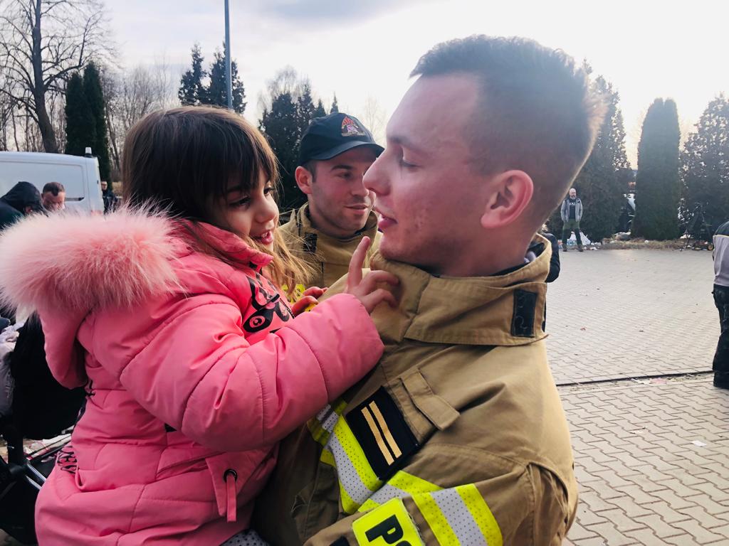 A Polish fireman holds a Ukrainian child, March 2022 (Lazar Berman/The Times of Israel)