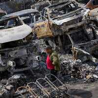 A Palestinian man walks between scorched cars in a scrapyard after a settler riot, in the town of Huwara, near the West Bank city of Nablus, February 27, 2023. (AP Photo/Ohad Zwigenberg)