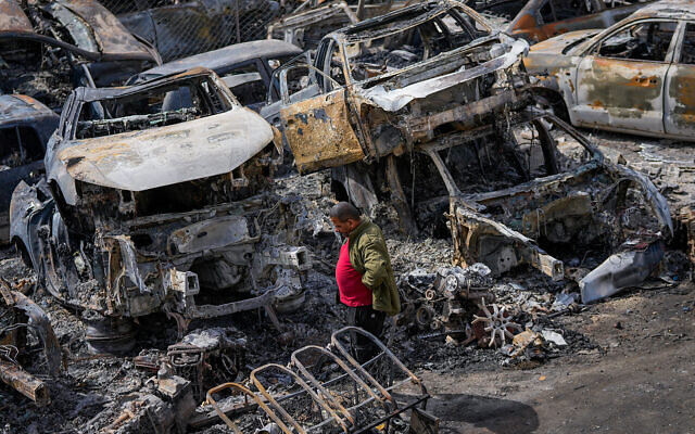 A Palestinian man walks between scorched cars in a scrapyard after a settler riot, in the town of Huwara, near the West Bank city of Nablus, February 27, 2023. (AP Photo/Ohad Zwigenberg)