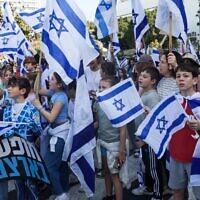 Children accompanied by their parents and guardians wave Israeli flags during a demonstration against the government's controversial judicial overhaul in Tel Aviv on March 1, 2023. (Jack GUEZ / AFP)