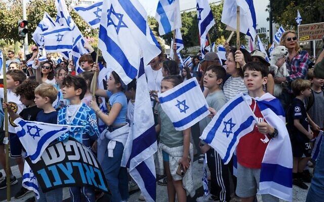 Children accompanied by their parents and guardians wave Israeli flags during a demonstration against the government's controversial judicial overhaul in Tel Aviv on March 1, 2023. (Jack GUEZ / AFP)