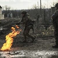 Ukrainian servicemen light a fire with gun powder to get warm near the city of Bakhmut in the region of Donbas on March 5, 2023, during the Russian invasion of Ukraine. (Aris Messinis / AFP)