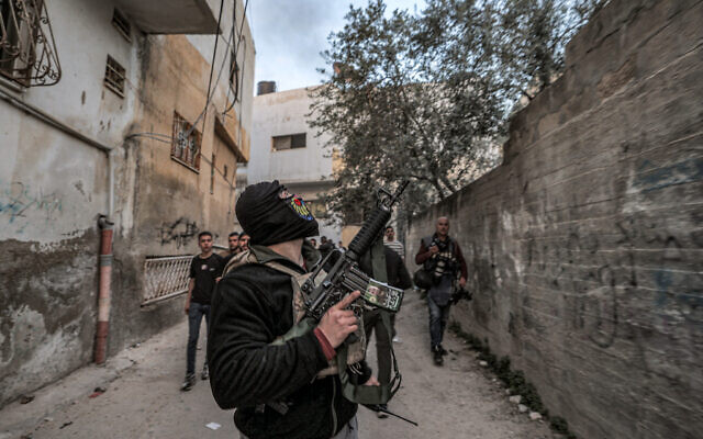 Masked Palestinian gunmen walk along an alley during an Israeli army raid in Jenin refugee camp, March 7, 2023.(Jaafar Ashtiyeh/AFP)