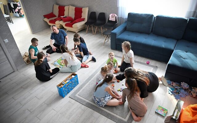 Russian pastor Roman Vinogradov (L) plays a board game with some of the 12 Ukrainian children he and his wife are fostering outside the Siberian city of Novosibirsk on March 10, 2023. (Alexander Nemenov/AFP)